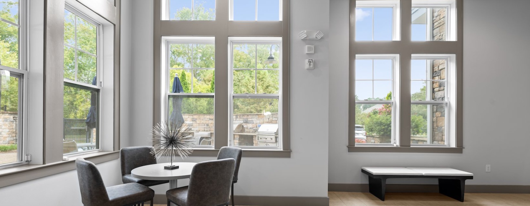 a room with a table and chairs and several large windows